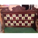 An art nouveau tiled splashback from a washstand, with two rows of tiles and carved crest.