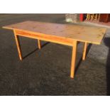 A rectangular pine dining table with extending leaf, raised on square column legs.