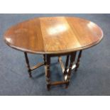 An oak drop leaf dining table with oval moulded top supported on baluster turned legs, joined by