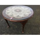 A circular mahogany coffee table with plate glass top and crochet mat cover raised on cabriole legs