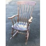 A slatback rocking chair with waved arms on spindles, raised on turned legs & stretchers with shaped