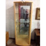 A contemporary display cabinet of bowfronted outline, with curved glass doors enclosing shelves.