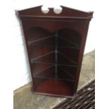 A mahogany corner cabinet with swan neck pediment above dentil moulding, the open compartment with