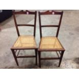A pair of Edwardian mahogany chairs with waisted cane seats raised on square tapering legs. (2)