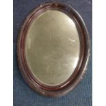 A large oval Edwardian mirror, the bevelled plate in bead moulded gesso frame.