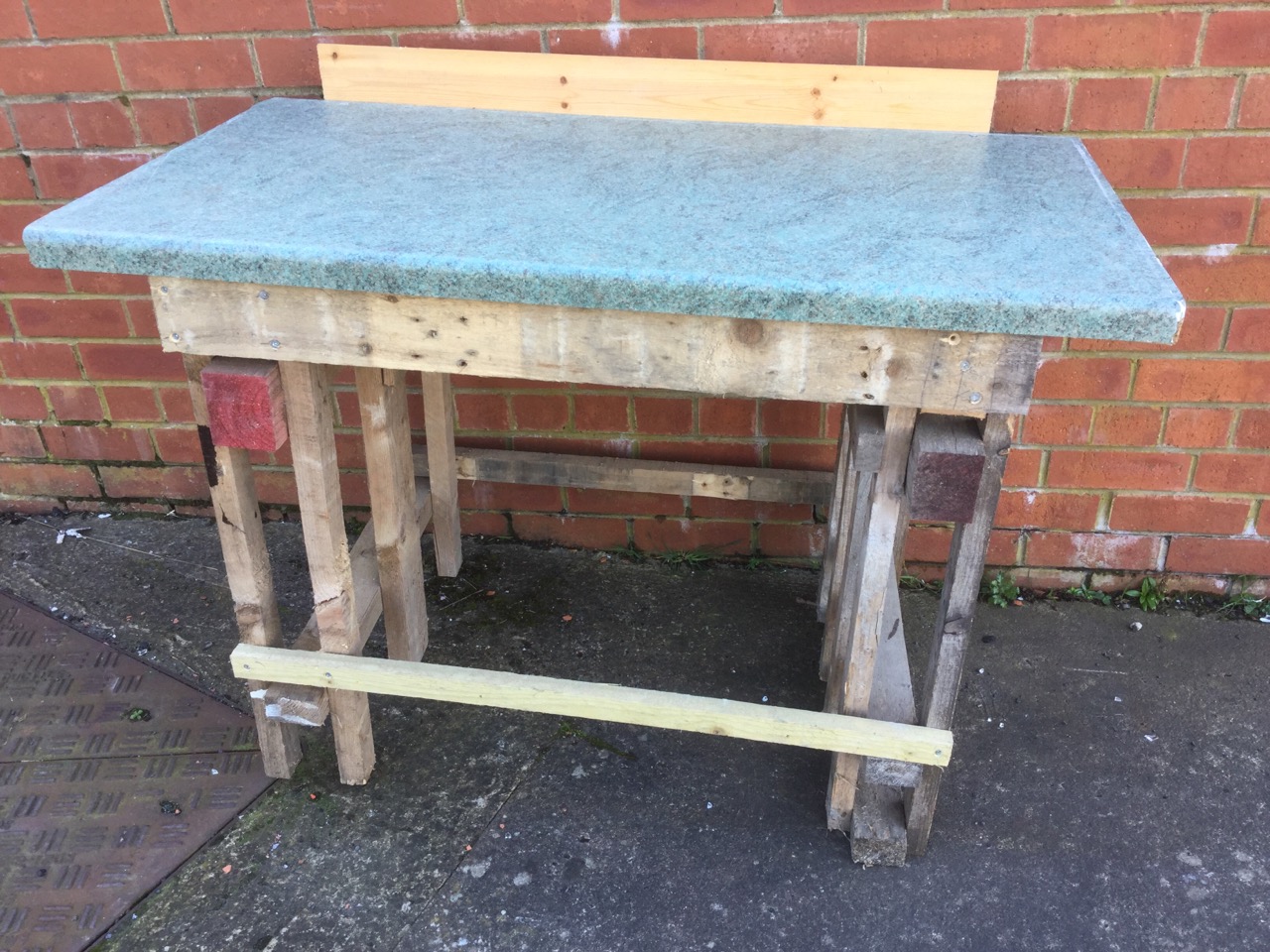 A homemade workbench with rectangular top supported on batton legs.