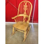 A beech rocking chair, the hooped back with pierced splat having shaped arms above a solid seat,