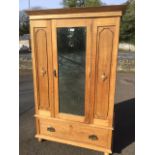 An oak wardrobe with angled cornice above a mirrored door flanked by panels