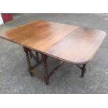 An Edwardian oak drop-leaf dining table, the rectangular moulded rounded top supported on barleytwis