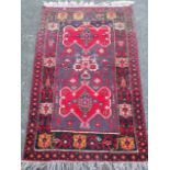 An oriental rug having charcoal grey field woven with scalloped red medallions, bordered by floral