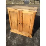 A pine cupboard with rectangular moulded top above fielded panelled doors