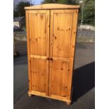 A pine wardrobe with arched crest above fielded panelled doors enclosing hanging space & shelf.