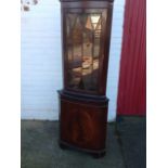 A mahogany corner cabinet with dentil cornice above astragal glazed door