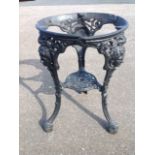 A cast iron pub style table base, the circular top on sabre supports cast with masks and paw feet.