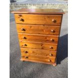 A reproduction pine chest with six drawers mounted with knobs on a moulded plinth raised on bun