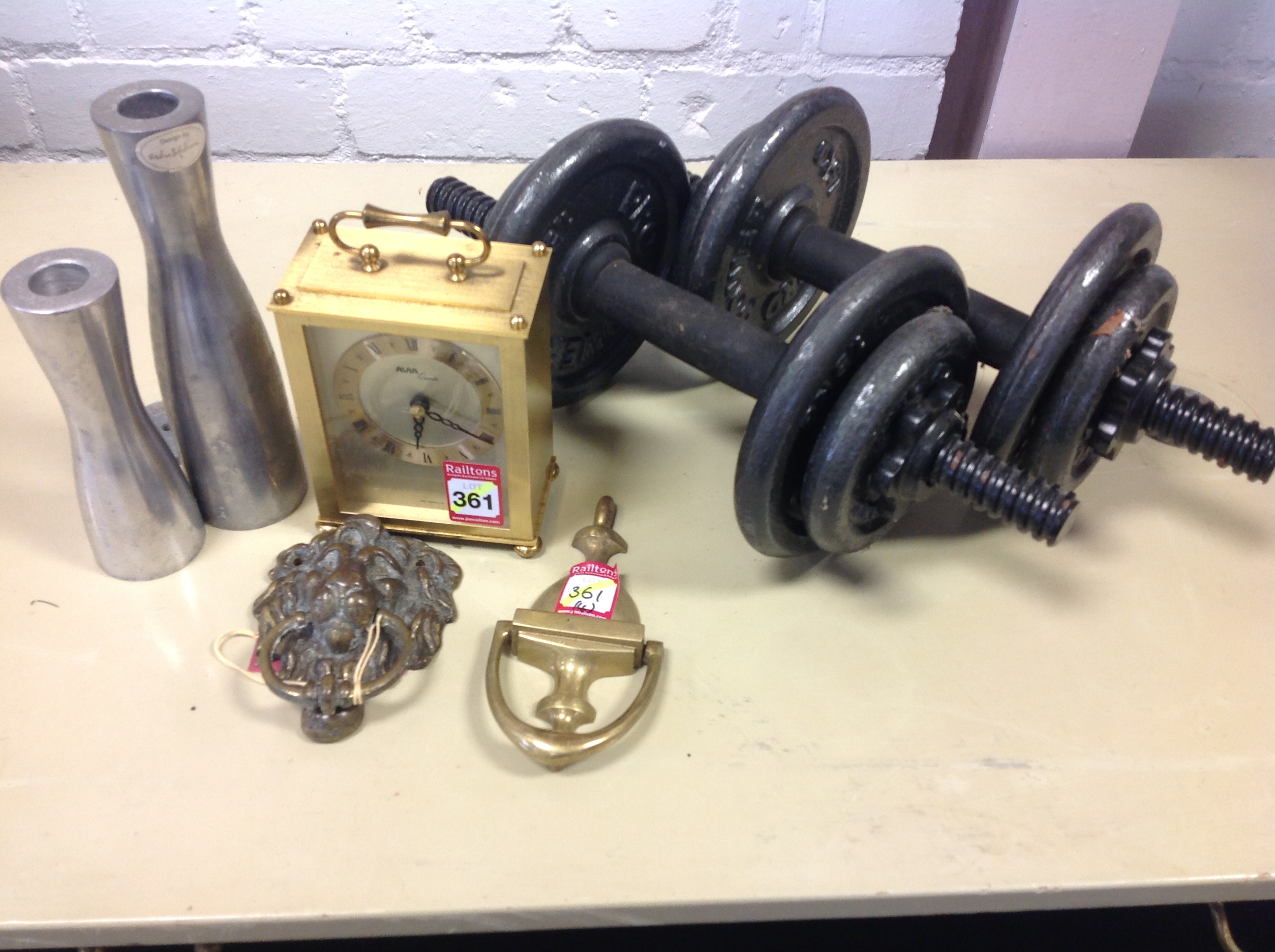 Two brass door knockers; a reproduction quartz carriage clock; and a graduated pair of steel candle