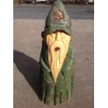 A chainsaw carved wizard, cut from a conifer tree trunk with green wood stain, scorched detailing