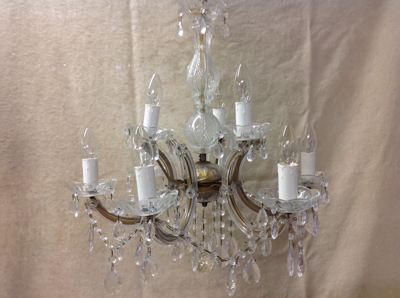 A glass chandelier with five branches around a fluted column, hung with glass drops and bead swags.