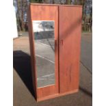 A teak style wardrobe, with later mirror to one door enclosing hanging space