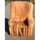 A chainsaw carved childs chair, cut from an oak treetrunk, with faux books below seat, and back