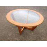 A circular teak coffee table, with plate glass insert to top, raised on shaped legs.