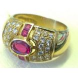 An 18ct gold ruby & diamond dress ring, the oval bezel set princess cut ruby framed by twin baguette