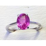 An 18ct white gold pink sapphire ring, the claw set oval stone of over two carats, set on a plain