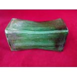 A Chinese head rest, the green glazed waisted colum with scrolled decoration to panels,