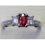 An 18ct white gold fancy sapphire and diamond ring, the oval claw set red sapphire bordered
