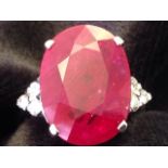 A large 18ct gold ruby & diamond ring, the claw set oval ruby of over eleven carats