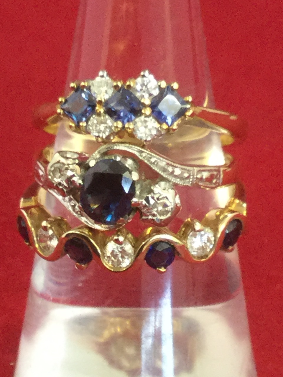 Three 18 carat gold diamond and sapphire rings, the bands claw set with contrasting stones. (3)