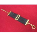 A 9 carat gold mounting mourning fob, the ribbon with buckles, scrolled bars & chains