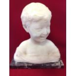 A carved marble bust of a boy, the smiling child mounted on variegated rectangular marble plinth.