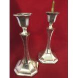 A pair of hallmarked silver candlesticks, with urn shaped candleholders above waisted octagonal