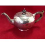 A bullet shaped hallmarked silver teapot with hinged lid, mounted with wood handle and finial