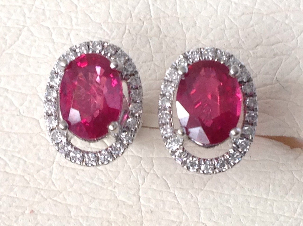 A pair of ruby and diamond cluster earrings, the claw set oval rubies of over two carats