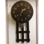 An arts & crafts ebonised oak wallclock, the circular dial with brass numerals and hands,