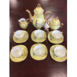 A cased Japanese porcelain coffee set with lemon lustre glaze and gilt handles decorated with geisha