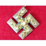 An antique jade swastika pendant, with gilt metal leaf style mounts set with seed pearls & diamonds