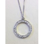 An 18ct white gold diamond pendant, the stones set in a circular ring, mounted on a fine hallmarked