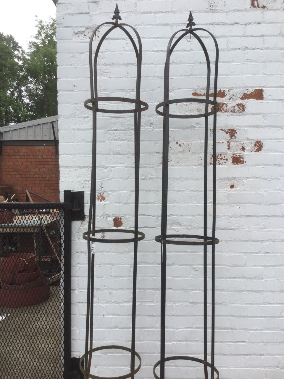 A pair of garden climbing towers of tubular form, bound with metal bands with spear finials. (2)