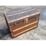 A domed top seamans chest, the slatted box with brass and iron mounts, raised on casters.