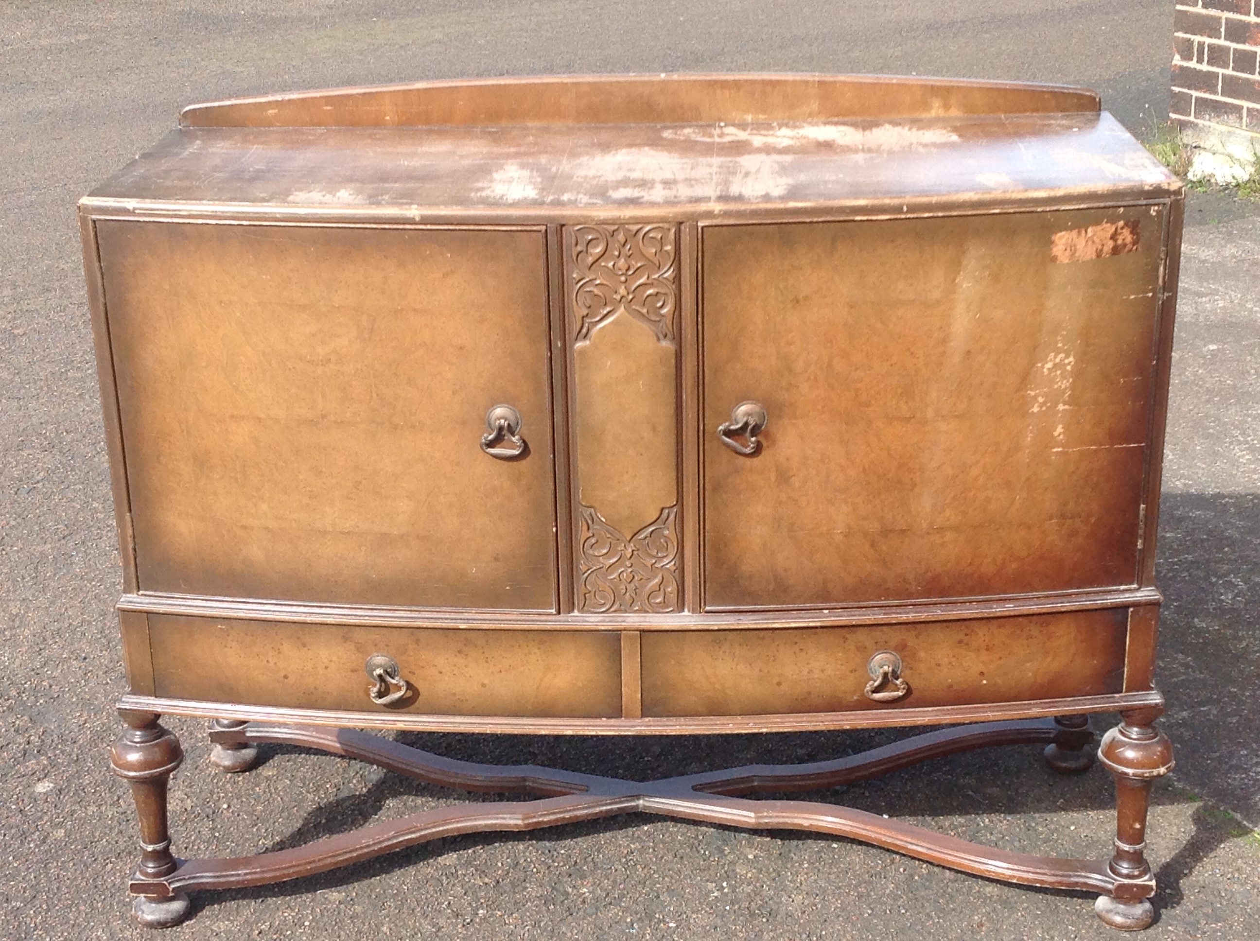 A bowfronted walnut sideboard, the moulded top above central carved panel flanked by panelled