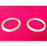 A pair of jade bangles, the circular rings of variegated colour. (2)