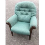 A modern armchair with arched button upholstered back above a sprung seat with cushion, raised on