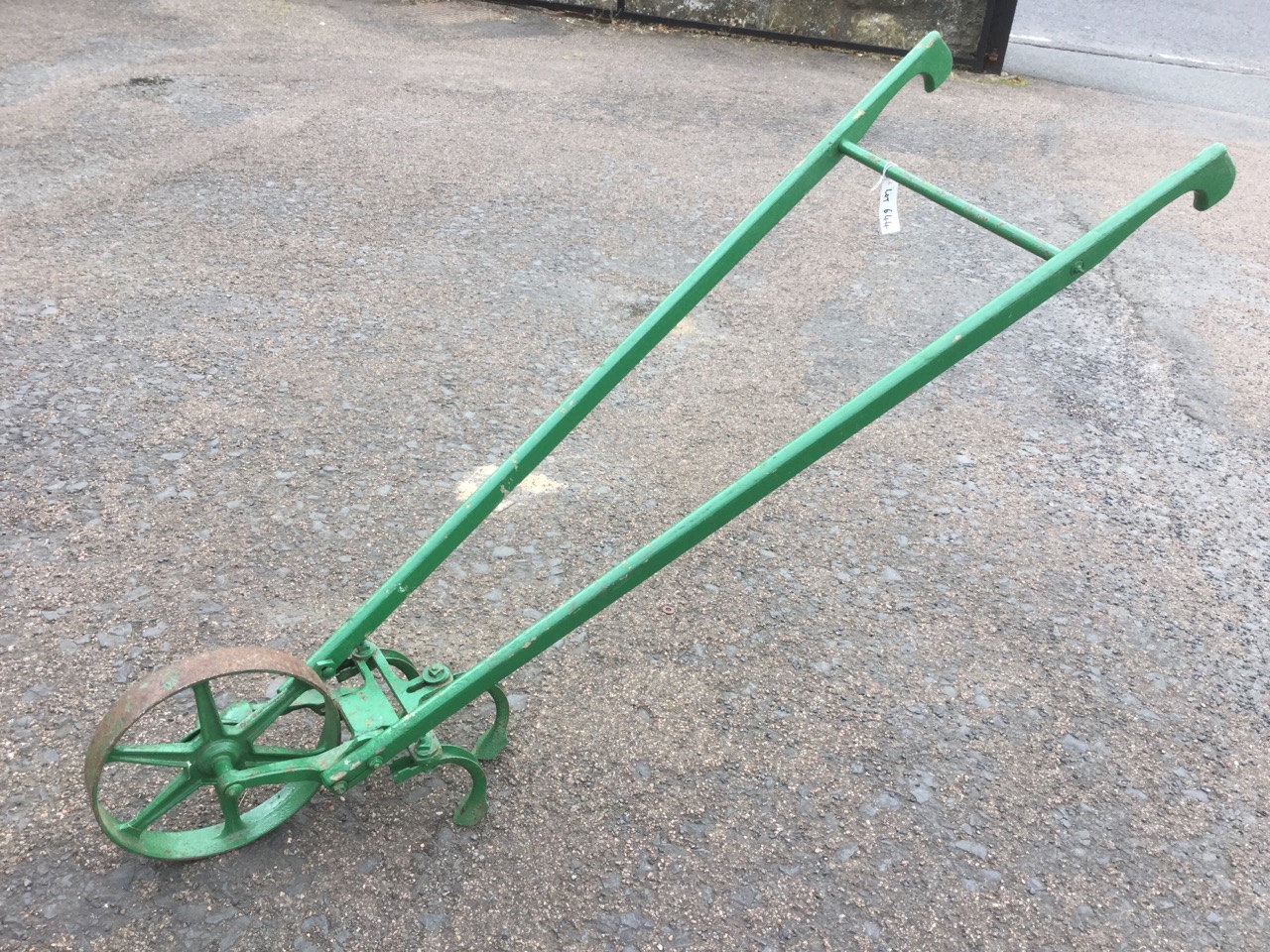 A hand harrow, with three shaped plough blades and cast iron wheel.