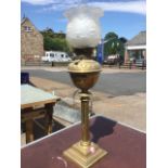 A Victorian brass oil lamp, with milk glass waved shade above a glass reservoir with cut decoration,