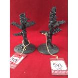 A pair of cast candlesticks modelled as golfers beneath oak trees, on circular naturalistic