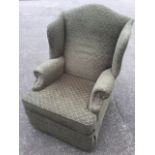 An upholstered reclining wing armchair, with arched back and loose cushion, the seat above an