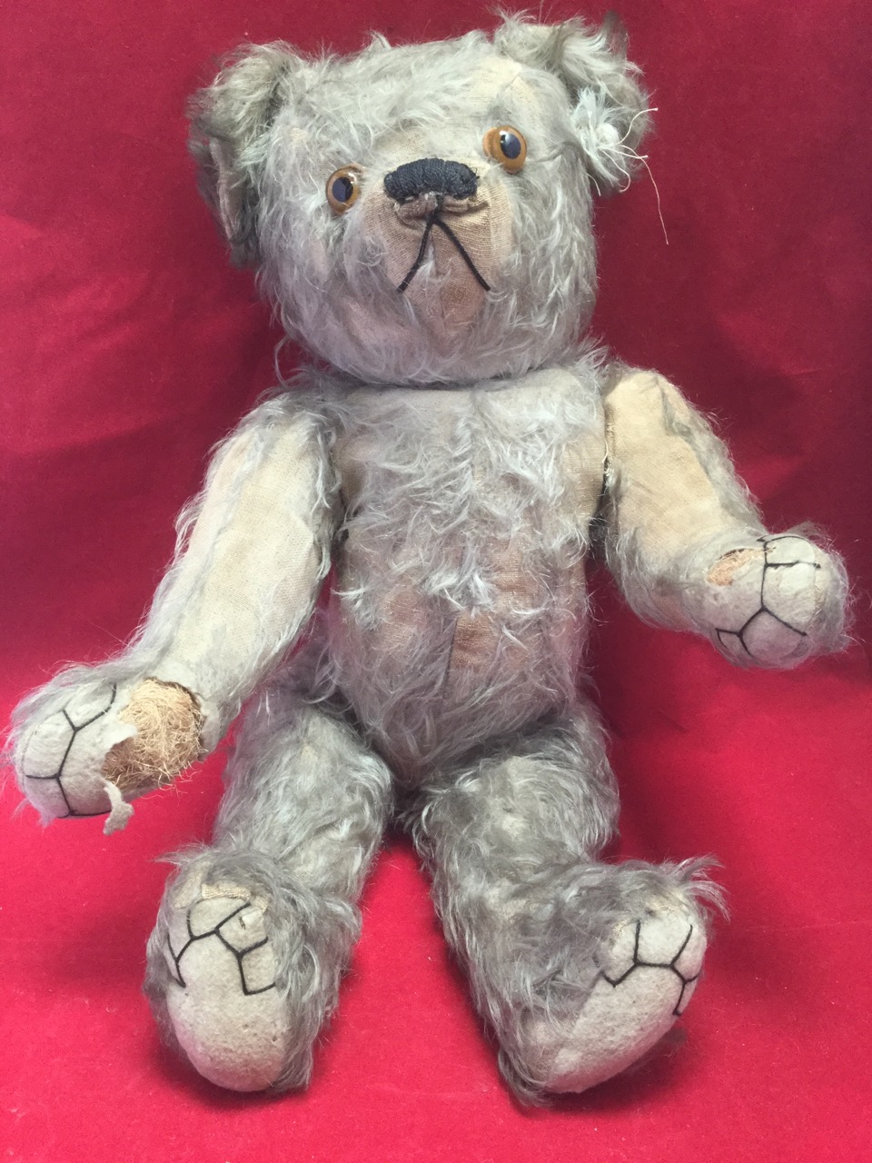 A large Edwardian plush bear, with stitched felt pads, articulated limbs and glass eyes, the snout